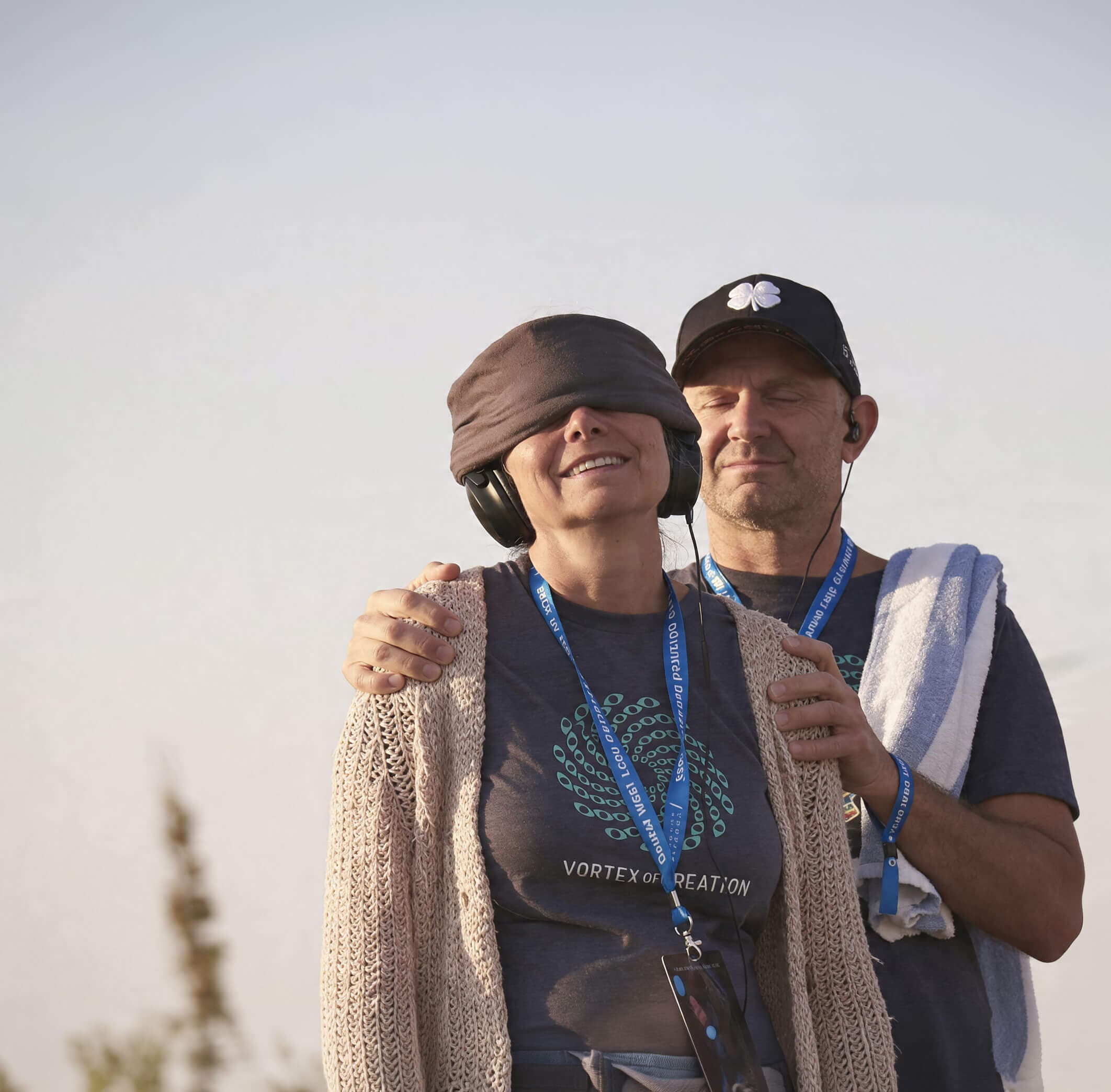 The founder Zack standing behind Katie at a Dispenza retreat, his hands on her shoulders, both wearing event lanyards
